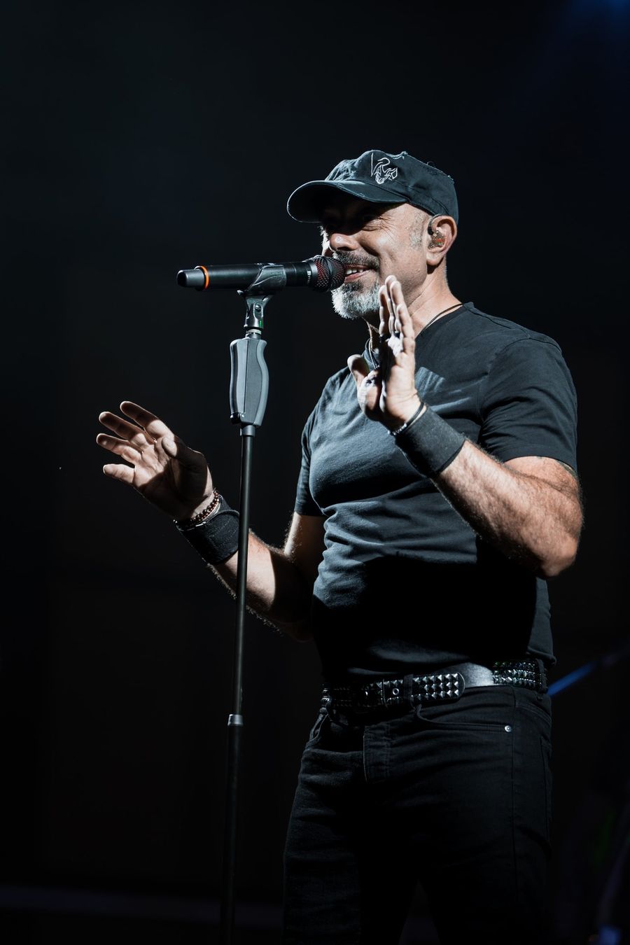 Il cantante dei Blascover al microfono, con il cappellino, su fondo nero