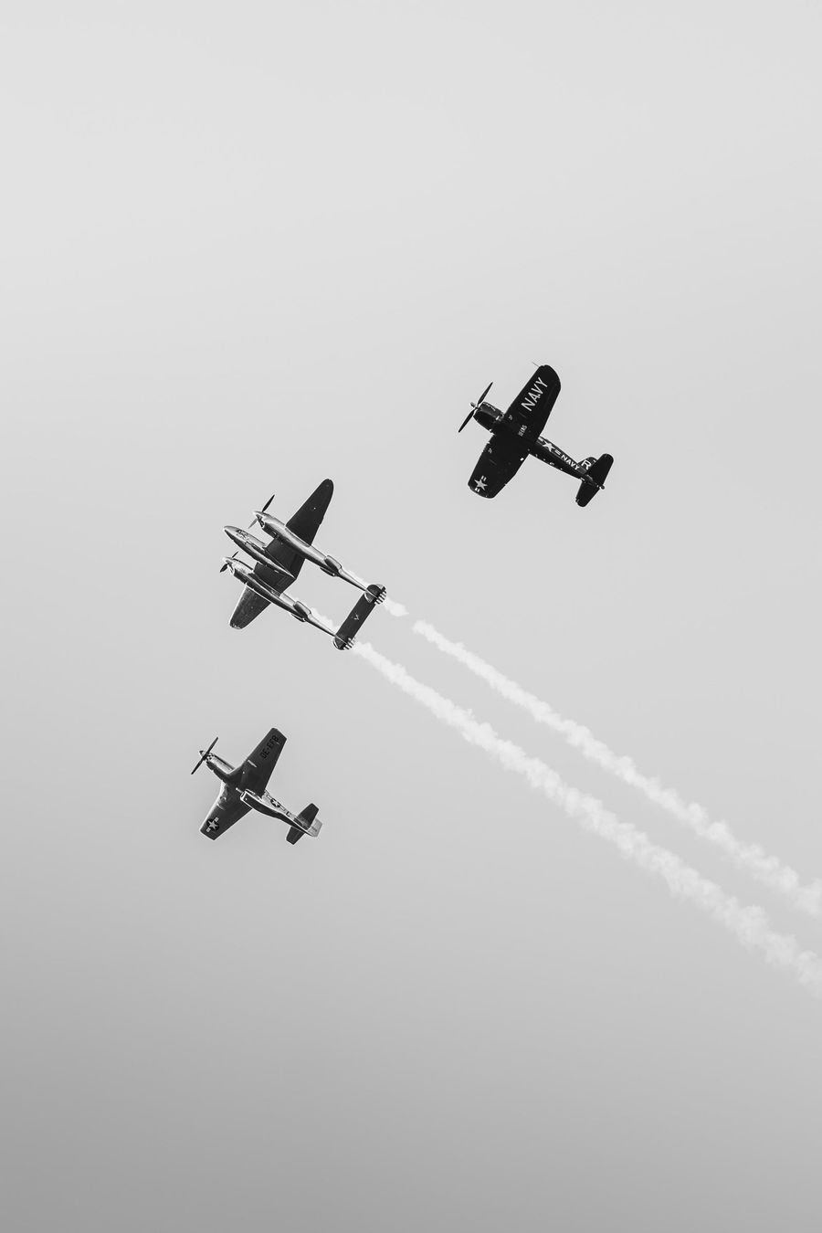 Tre aerei storici in formazione con le scie bianche, cielo grigio