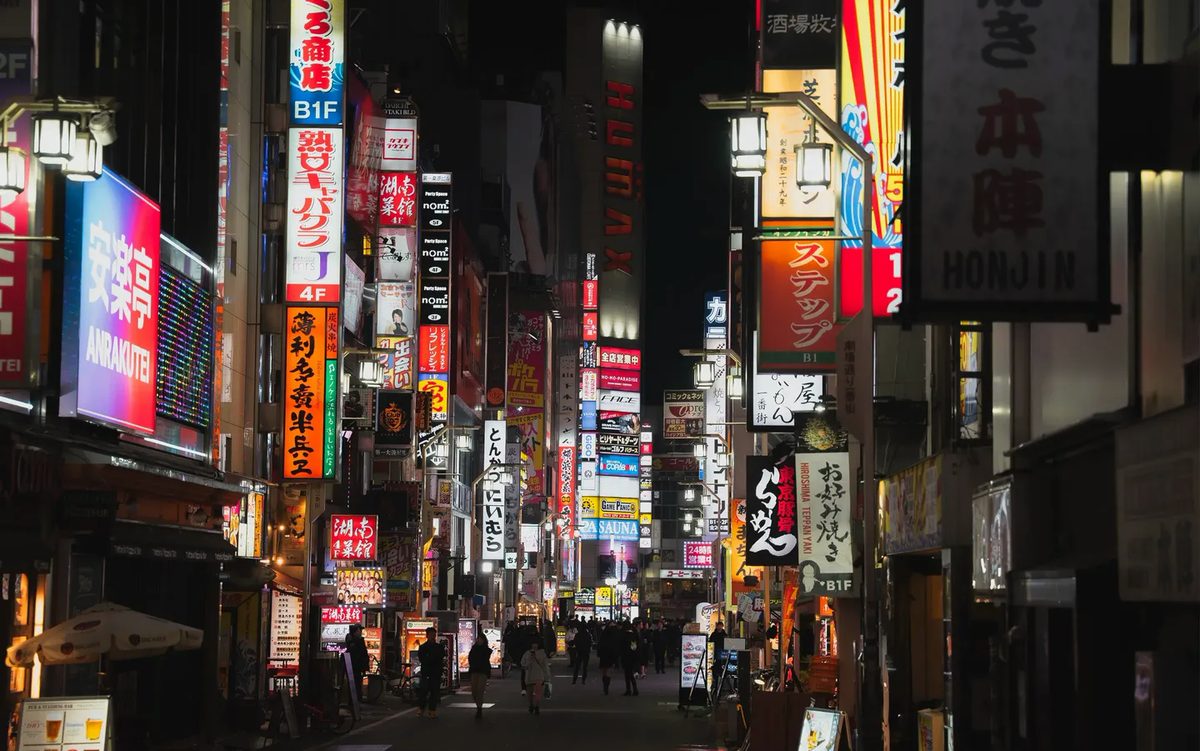 Una via di Tokyo di notte, con le insegne accese su ogni palazzo