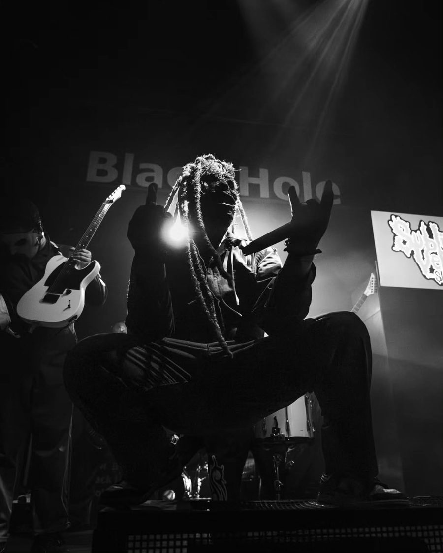 Il cantante dei Subliminal Verses accovacciato sul palco nel fumo, in bianco e nero