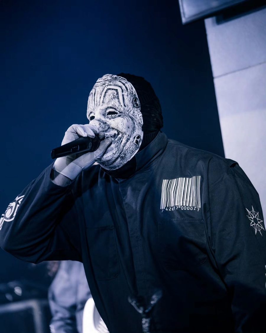 Il cantante dei Subliminal Verses con la maschera bianca e il codice a barre sulla tuta, in luce blu