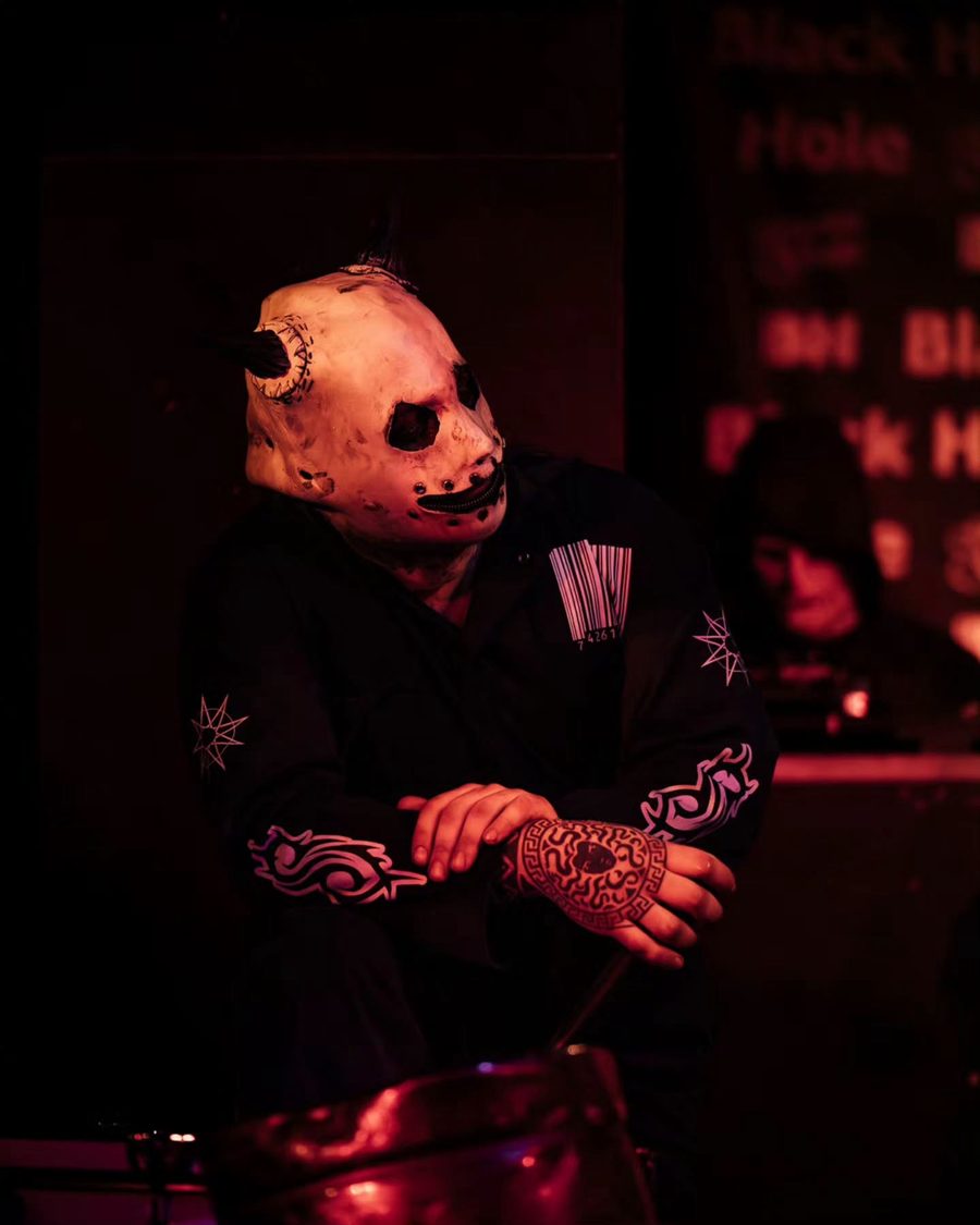 Il percussionista dei Subliminal Verses con la maschera, in luce rossa