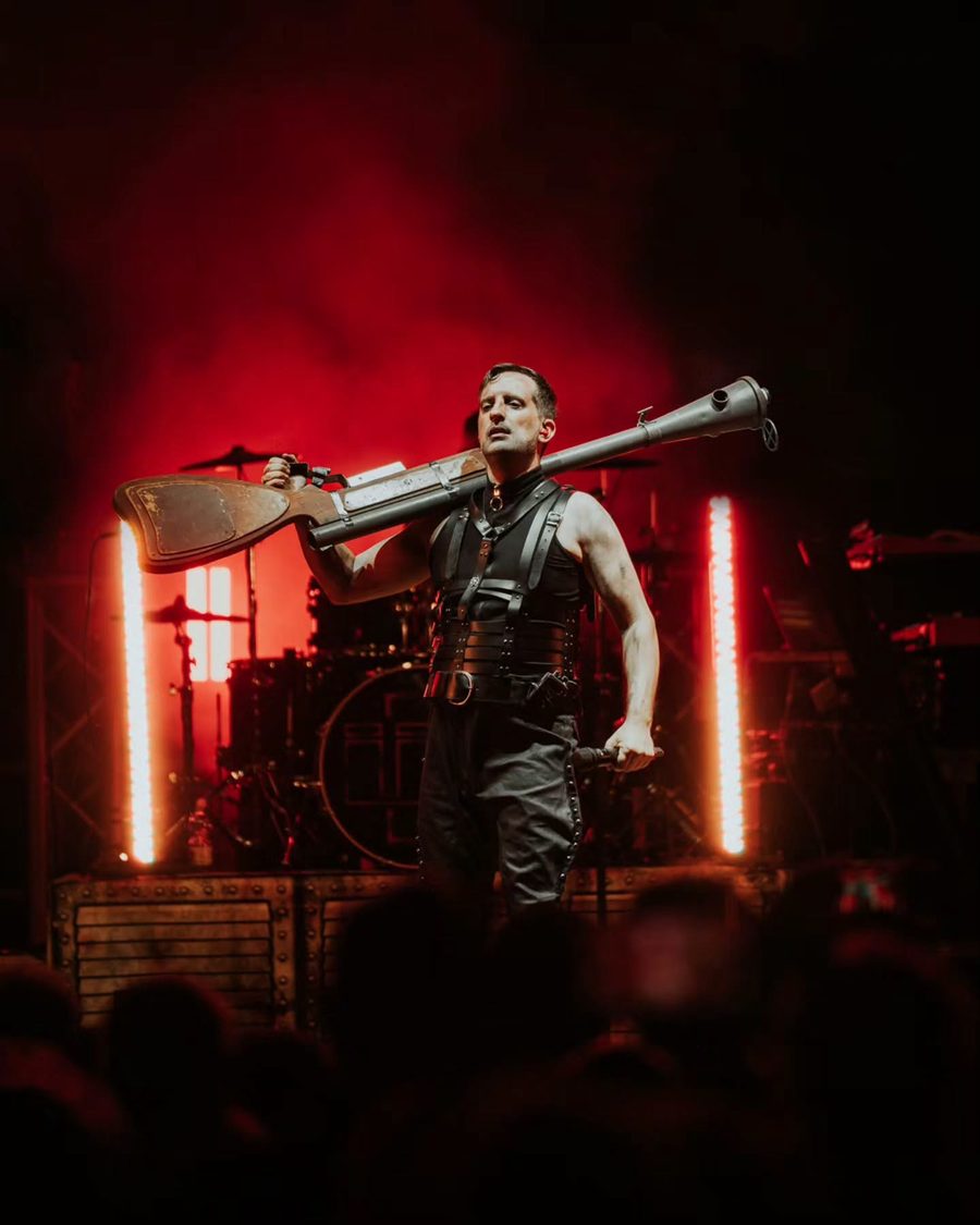 Il cantante degli Übermensch con un cannone di scena in spalla, sotto le luci rosse