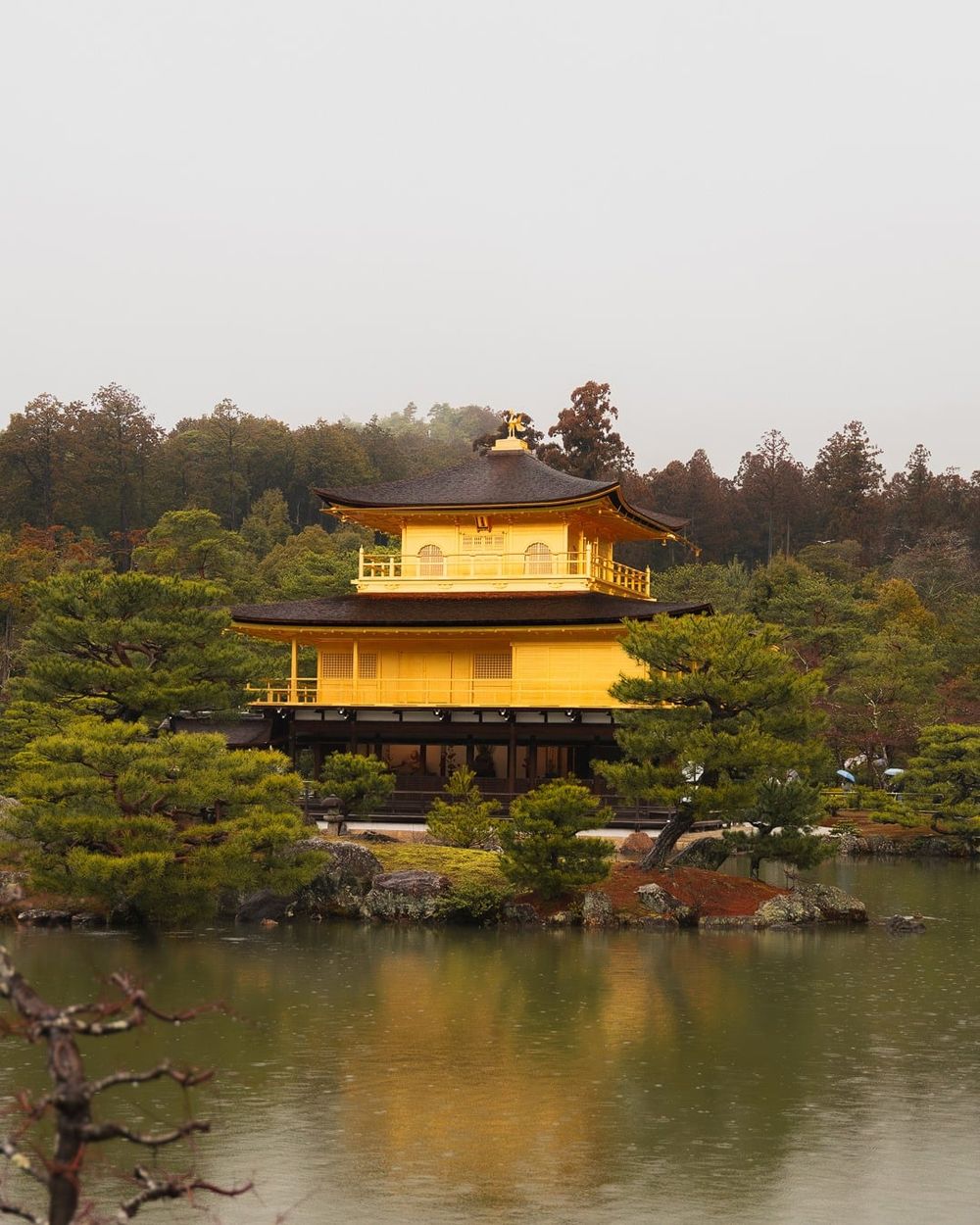 Il padiglione d'oro di Kinkaku-ji riflesso nel lago, sotto la pioggia